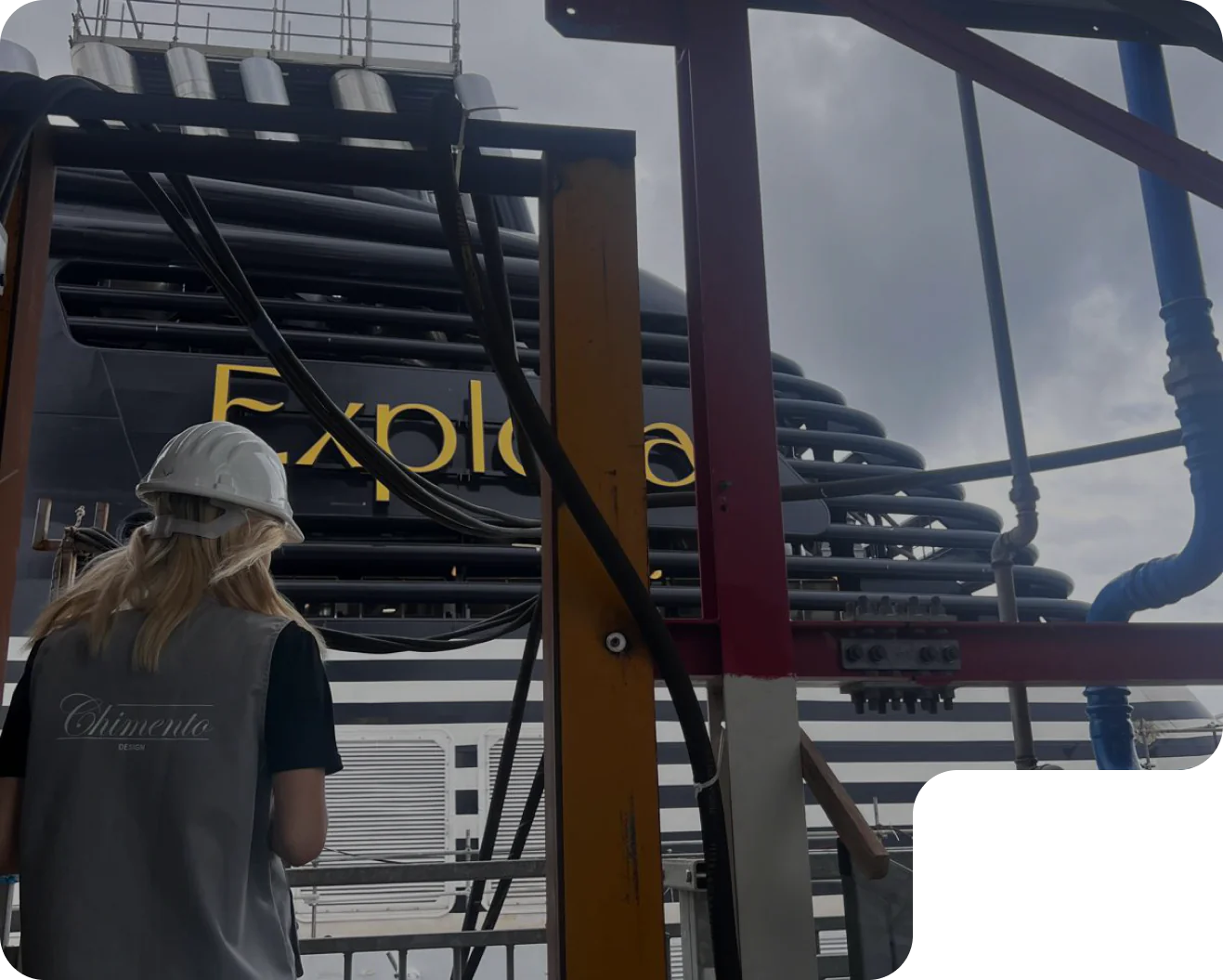 A Chimento Design team member in a hard hat beside the hull of an Explora Journeys ship